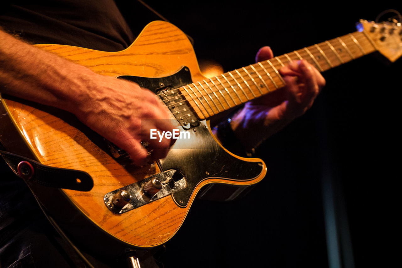 Midsection of musician playing guitar