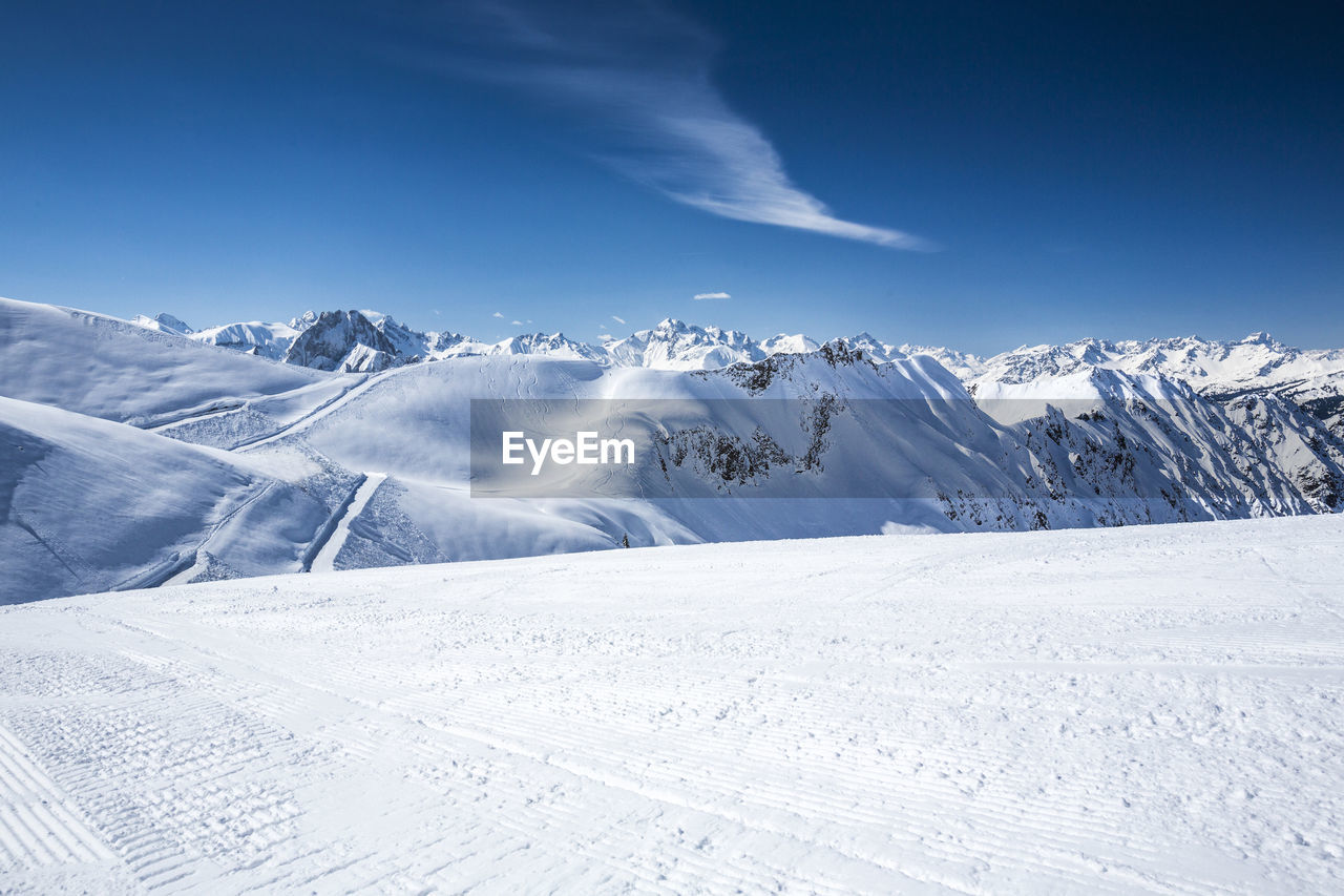 Scenic view of snow mountains against blue sky