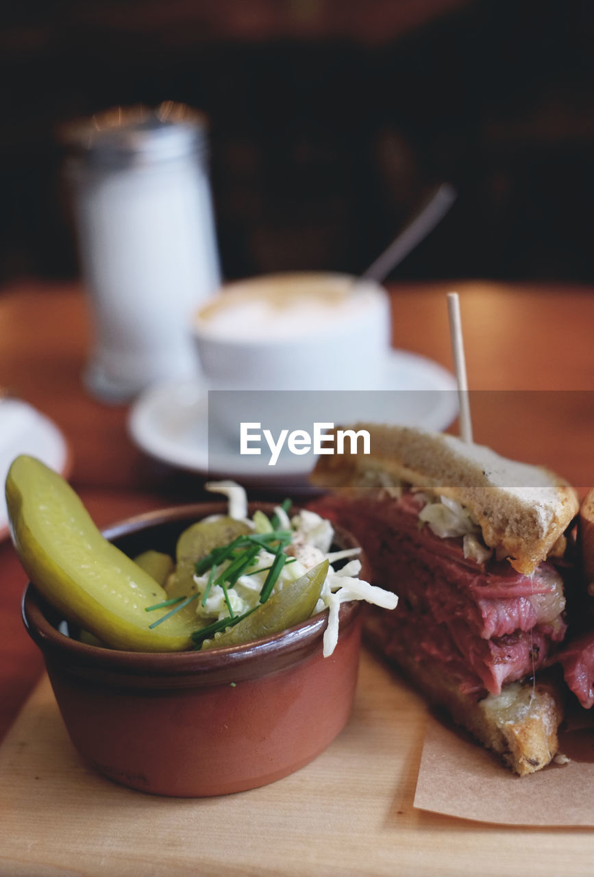 Close-up of pastrami sandwich and pickles on tray