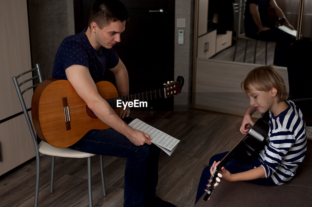 High angle view of instructor teaching guitar to boy