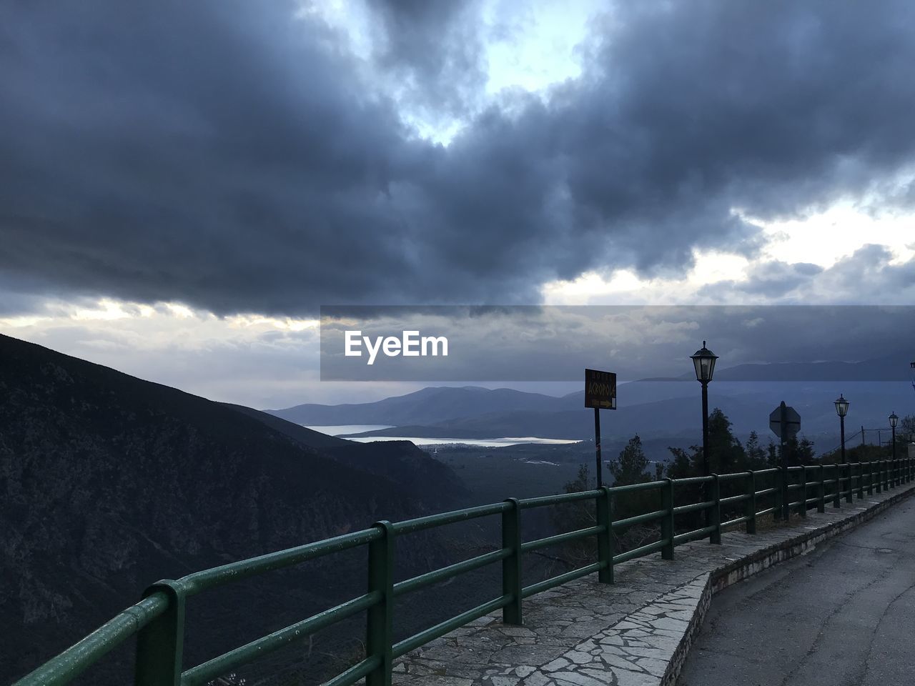 cloud, sky, railing, nature, environment, horizon, dramatic sky, storm, mountain, scenics - nature, beauty in nature, architecture, storm cloud, overcast, landscape, morning, cloudscape, road, footpath, the way forward, sunlight, street, transportation, outdoors, no people, sea, darkness, city, dusk, fence, dark, travel destinations, tranquility, built structure, water, travel, tranquil scene, moody sky, mountain range