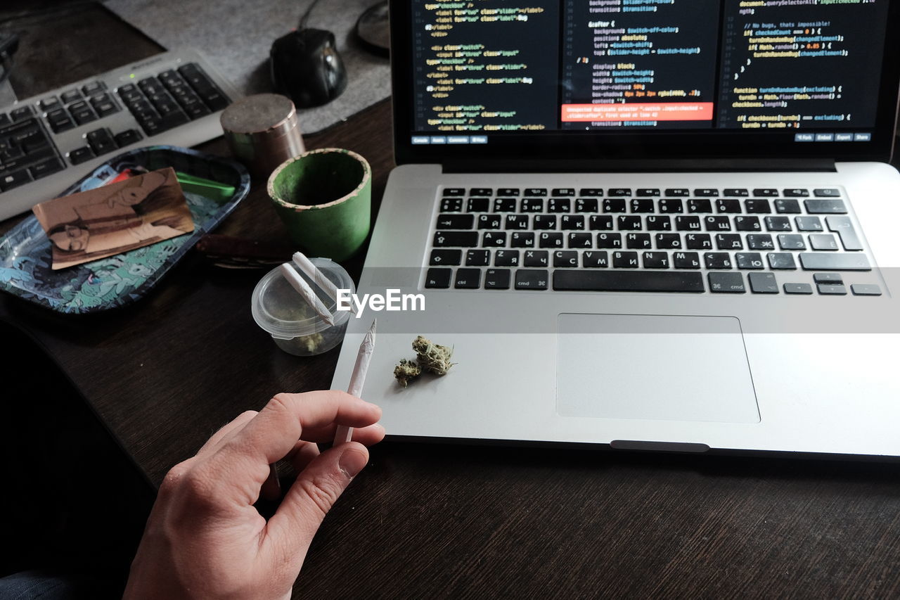 cropped hands of woman using laptop on table