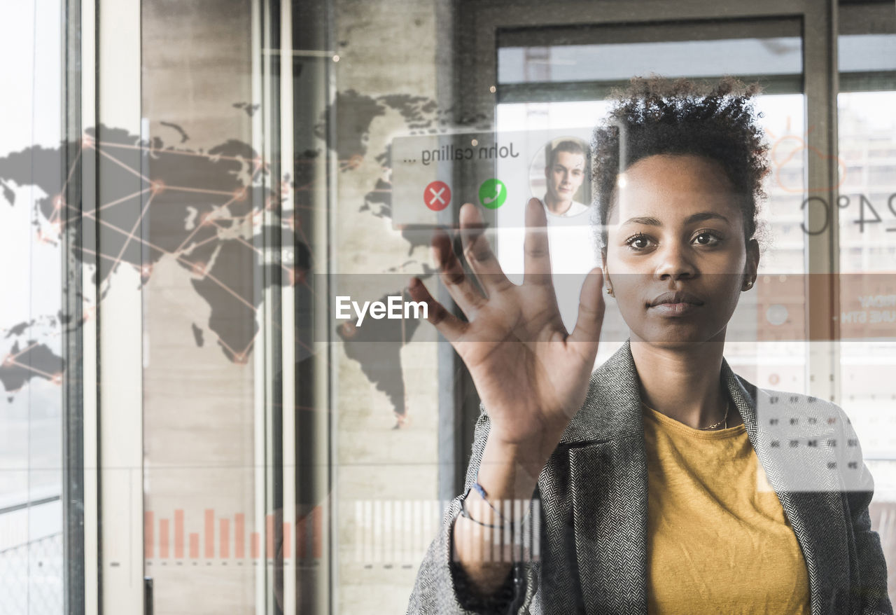 Young woman receiving a call on glass wall with world map in office