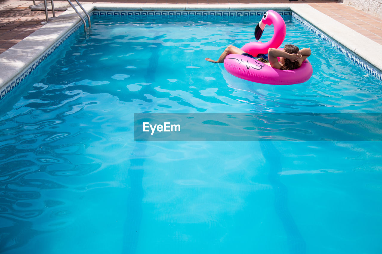 HIGH ANGLE VIEW OF WOMAN SWIMMING IN WATER