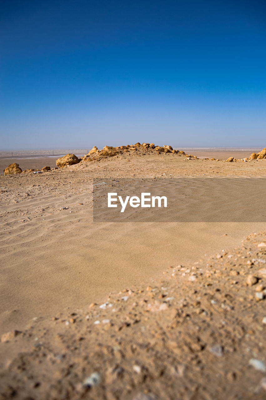 SURFACE LEVEL OF SAND DUNES AGAINST CLEAR SKY