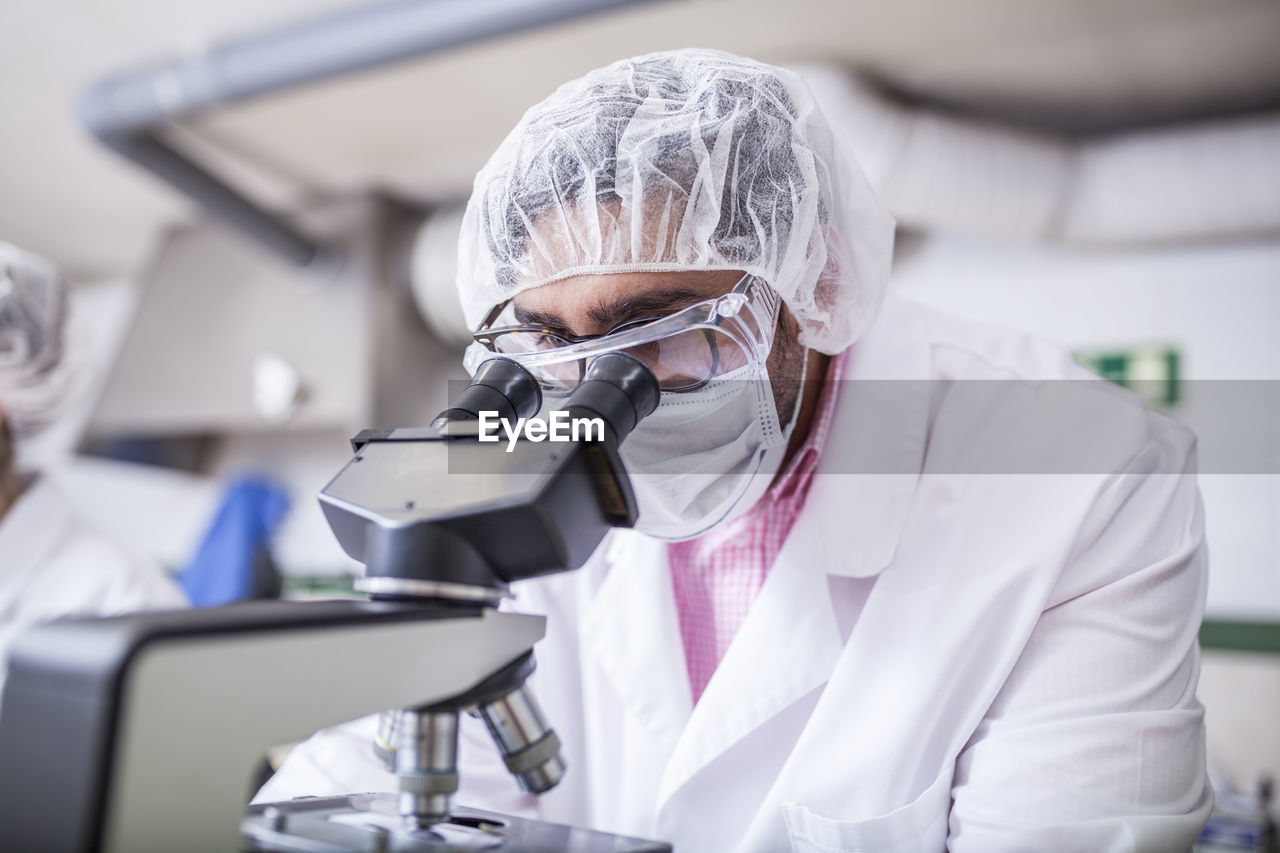 Man scientist looking through microscope at laboratory