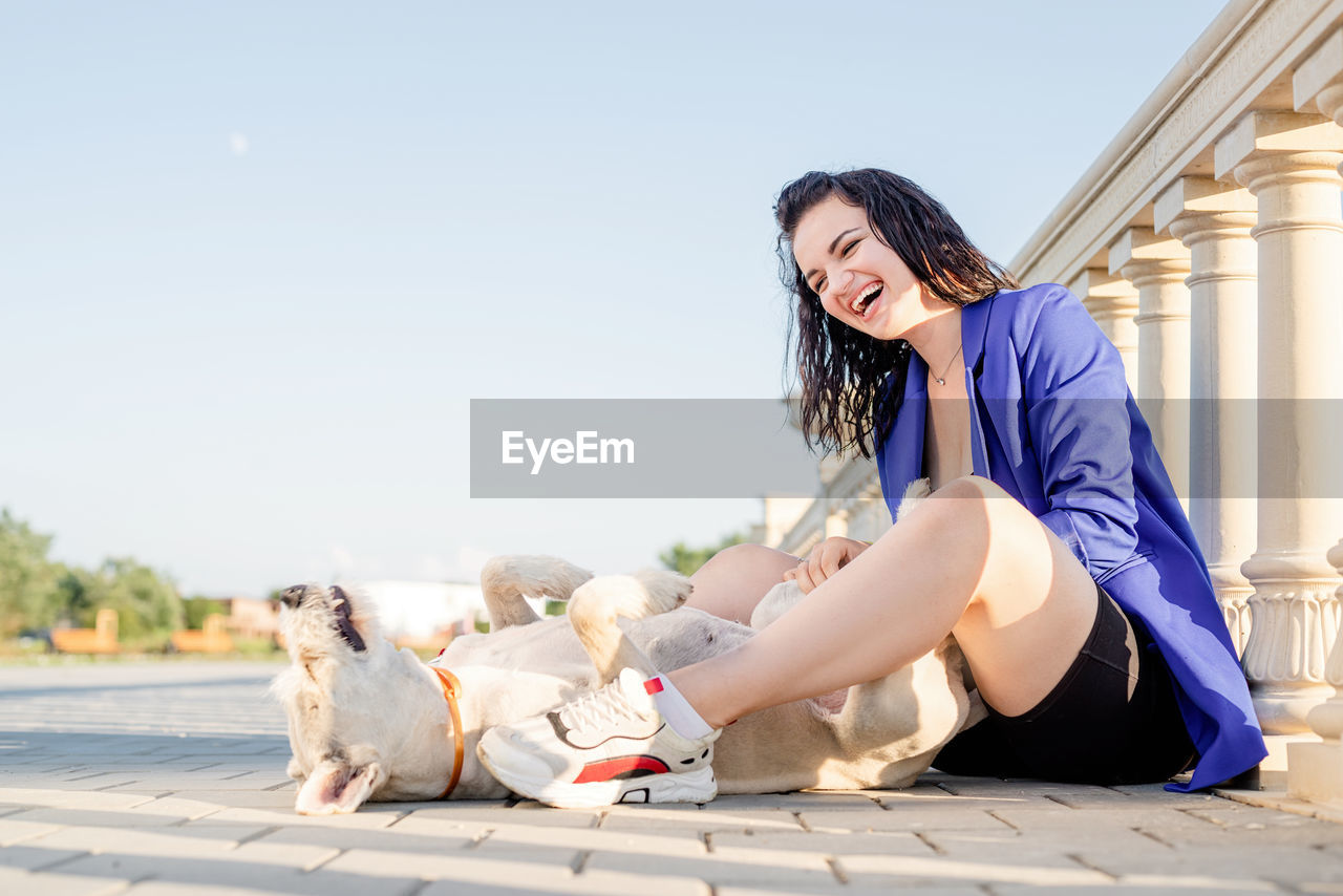 Woman with dog sitting outdoors laughing