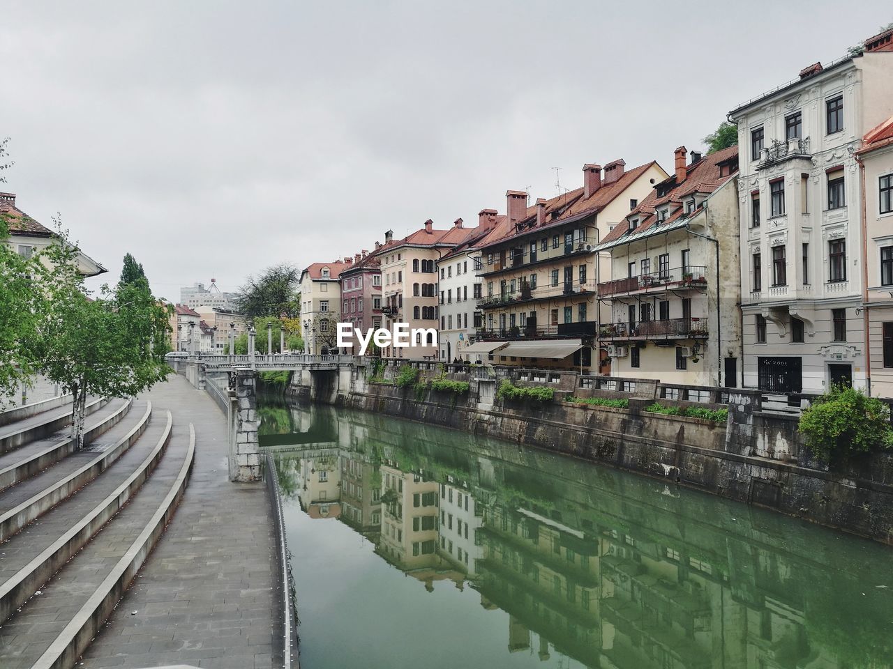 Canal by buildings against sky