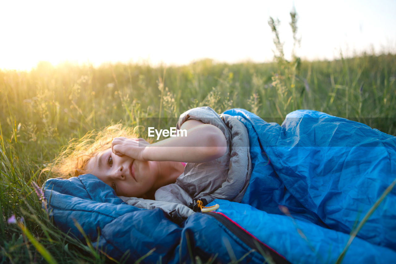 Cute girl in sleeping bag on field