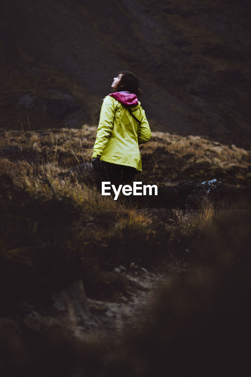 REAR VIEW OF WOMAN WITH UMBRELLA WHILE WALKING ON LAND