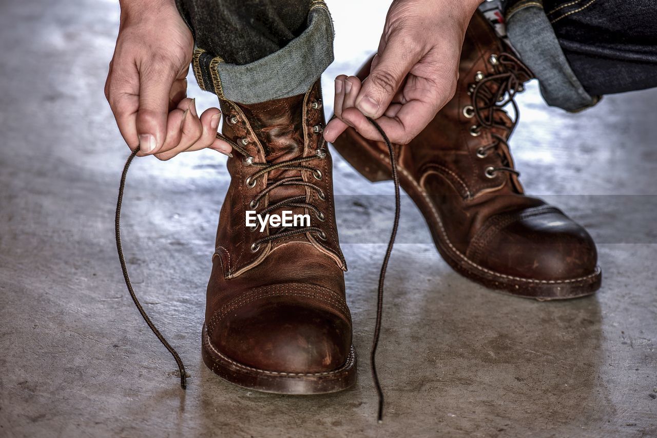 Low section of man tying shoelace