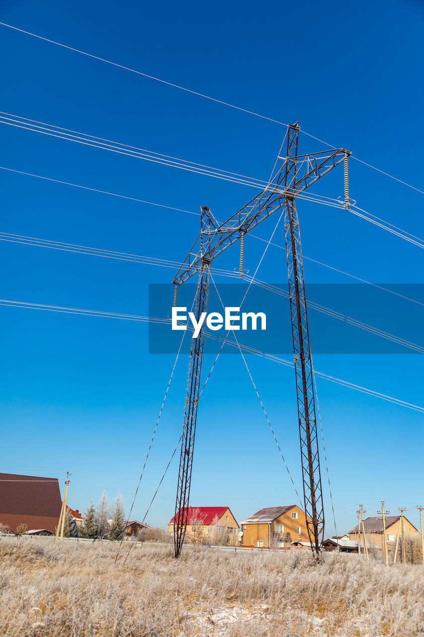 LOW ANGLE VIEW OF ELECTRICITY PYLON ON FIELD AGAINST CLEAR SKY