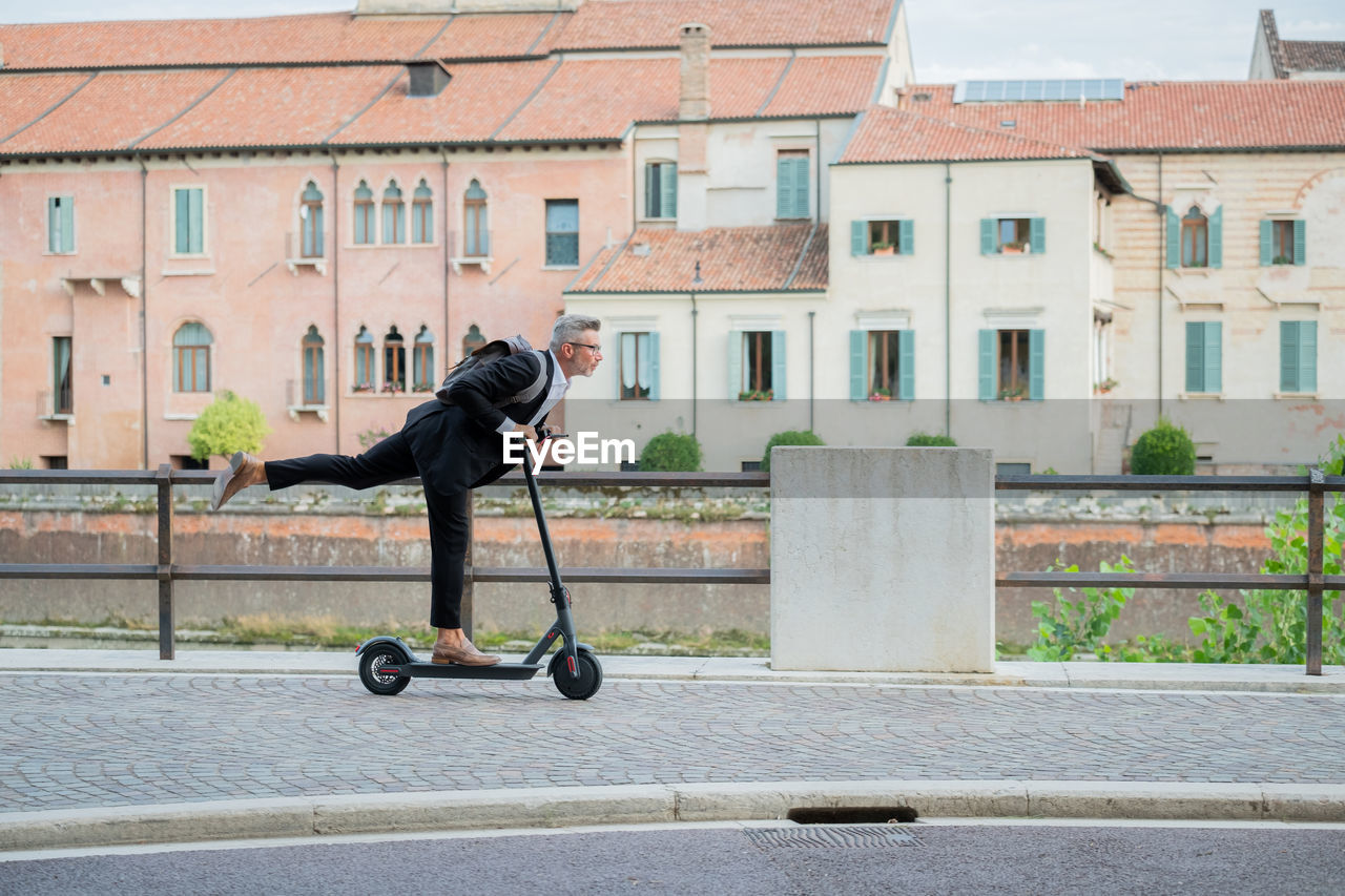 Man riding skateboard on street against buildings in city