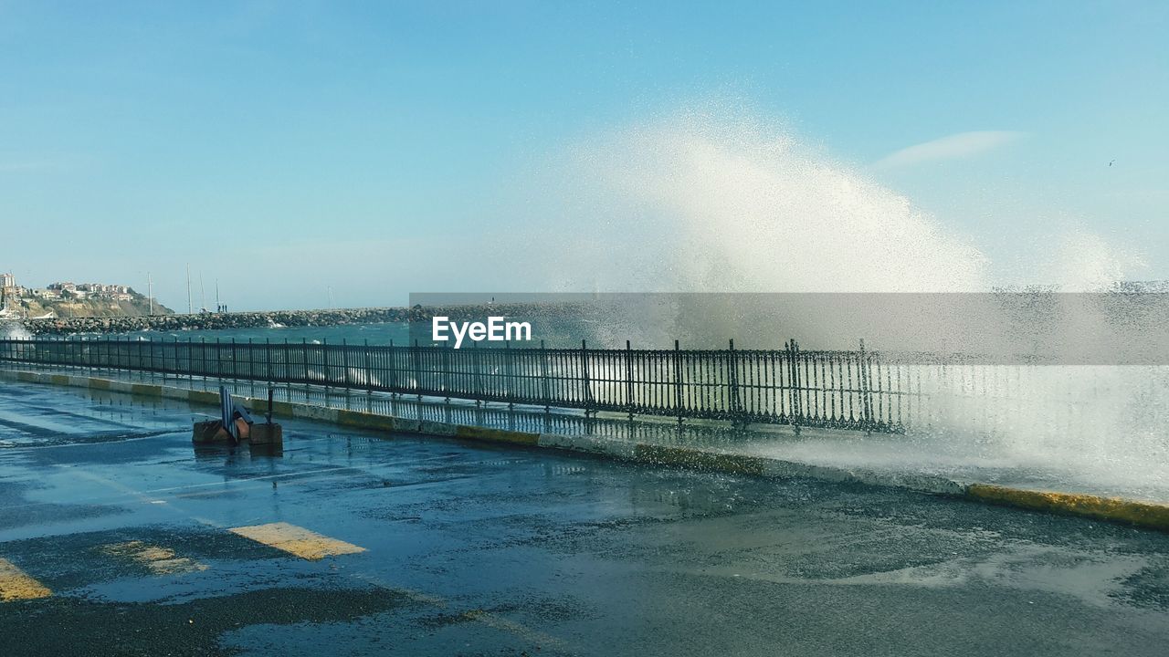 Waves splashing on shore against sky