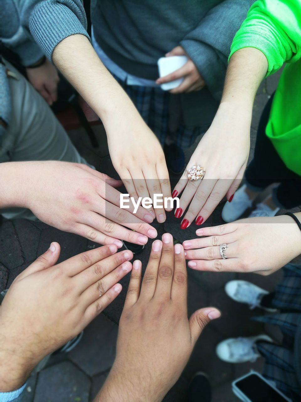 High angle view of friends showing hands while huddling outdoors