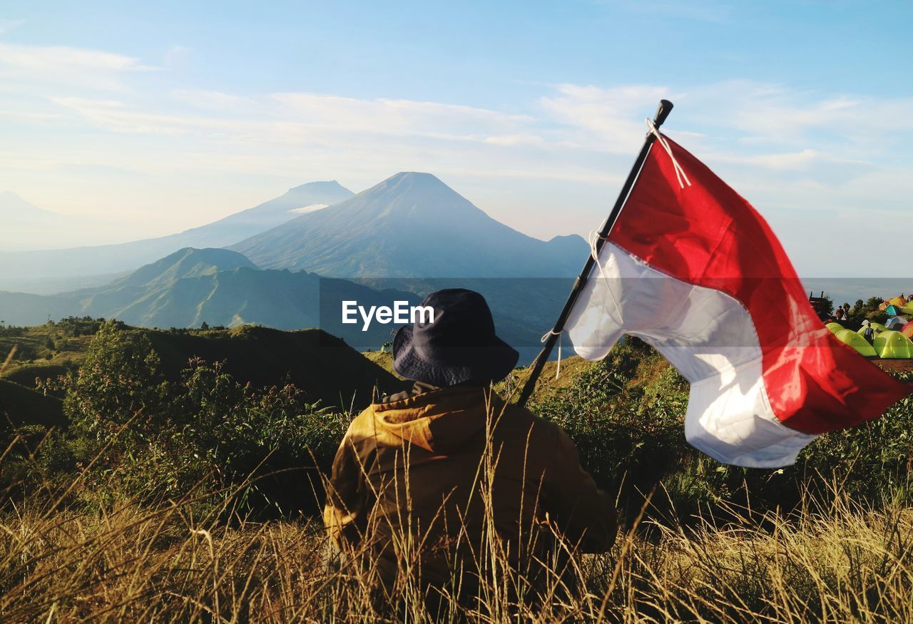 Rear view of woman standing on field against sky