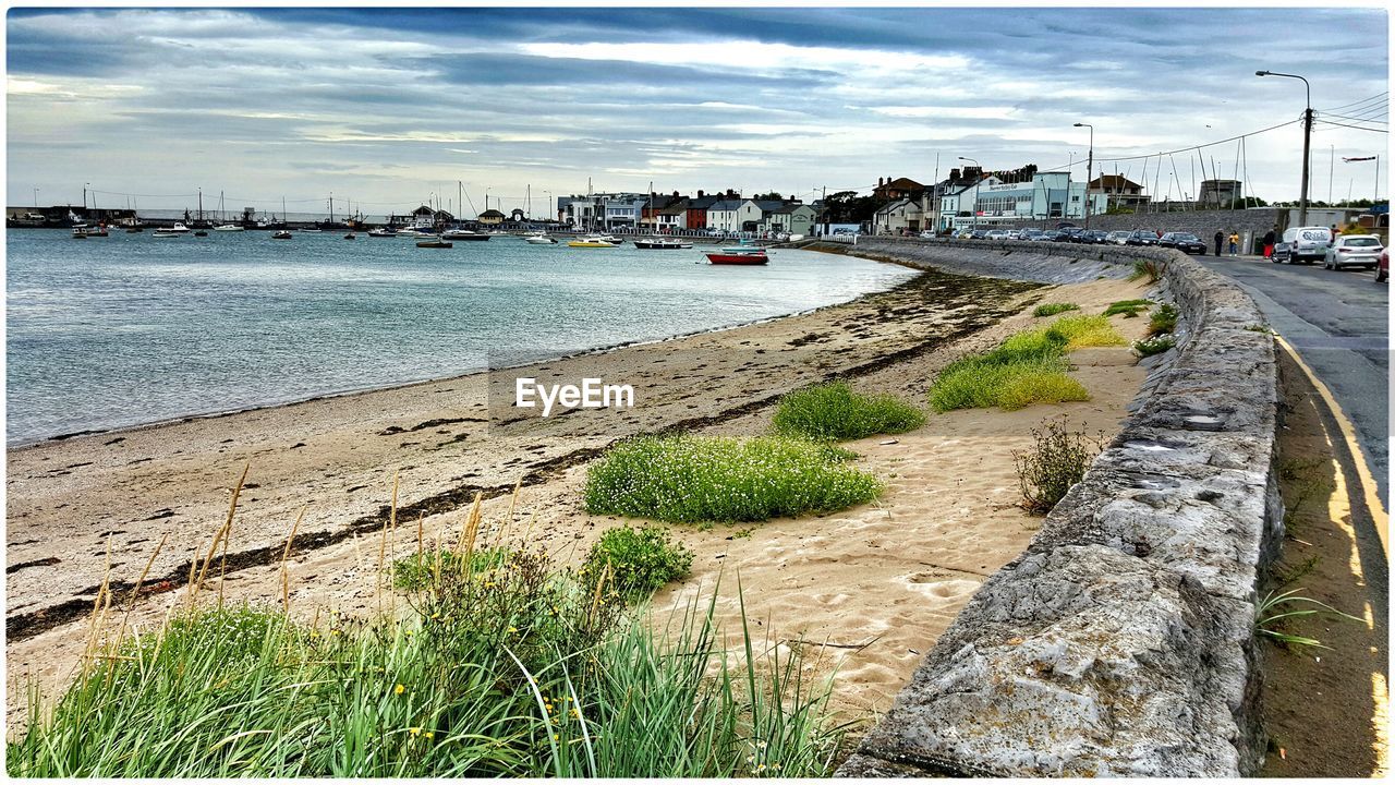 High angle view of sea shore by road against cloudy sky