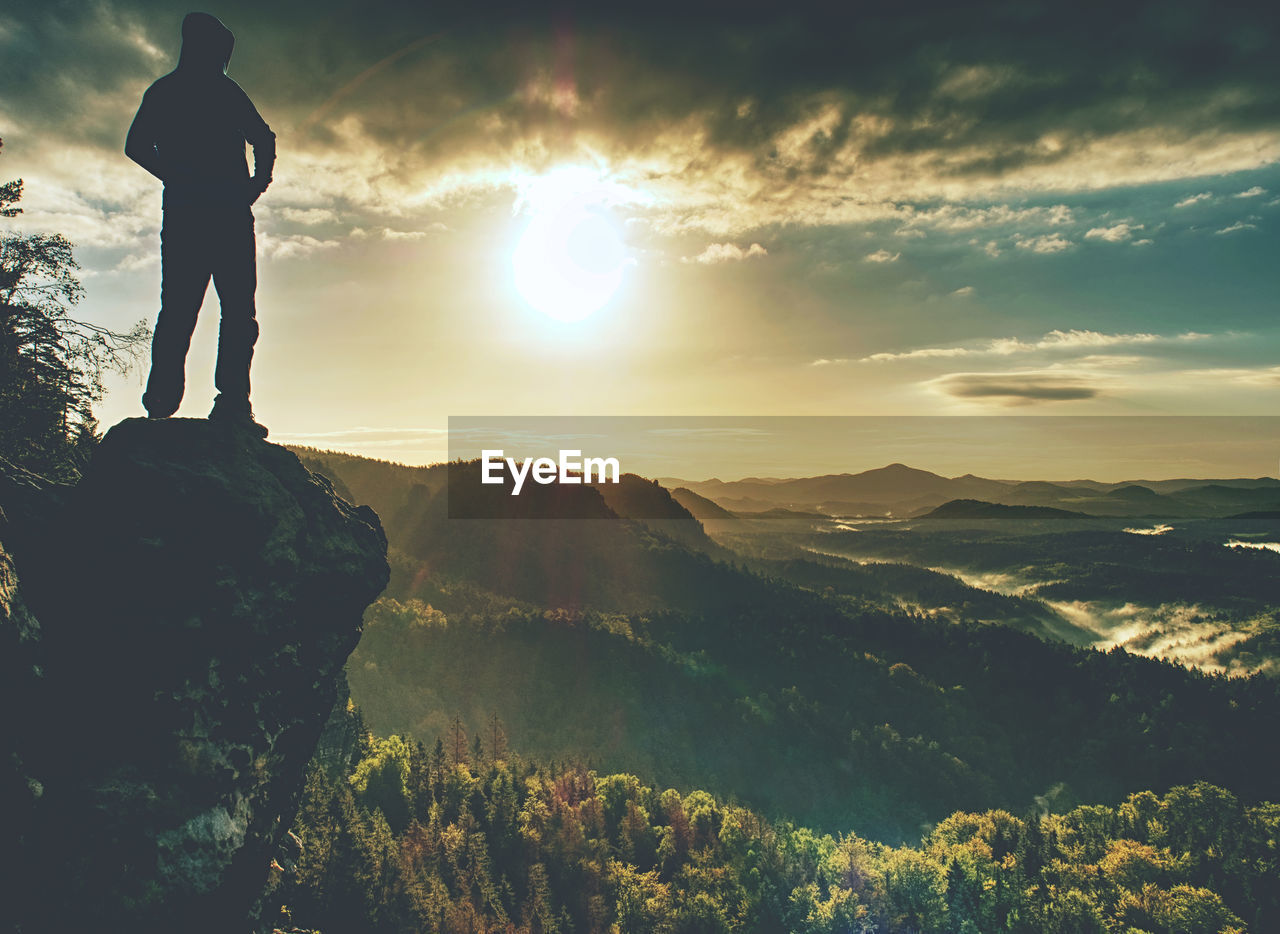 Moment of loneliness. man on the rock empires and watch over the misty landscape