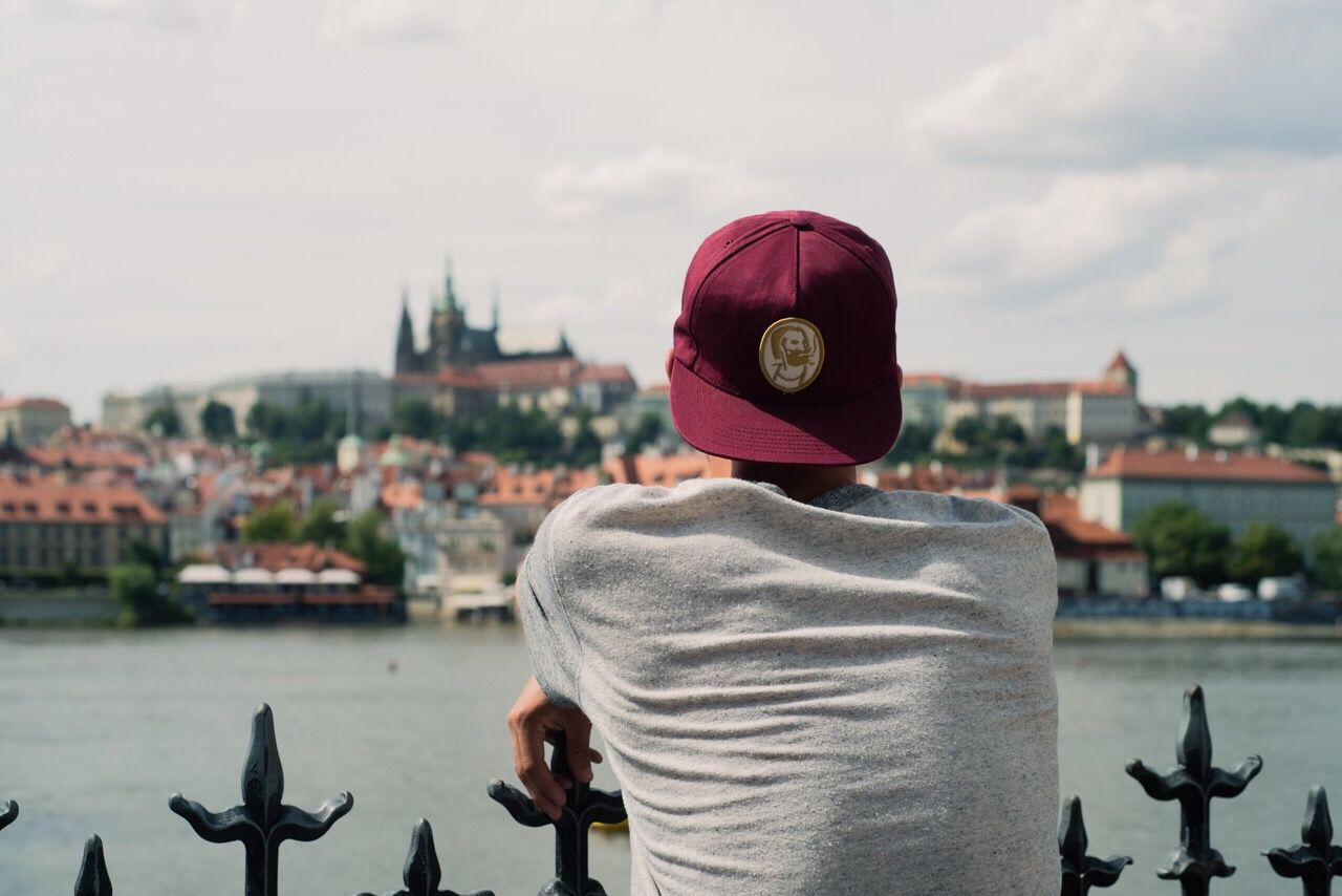 Rear view of man standing at riverbank looking at town