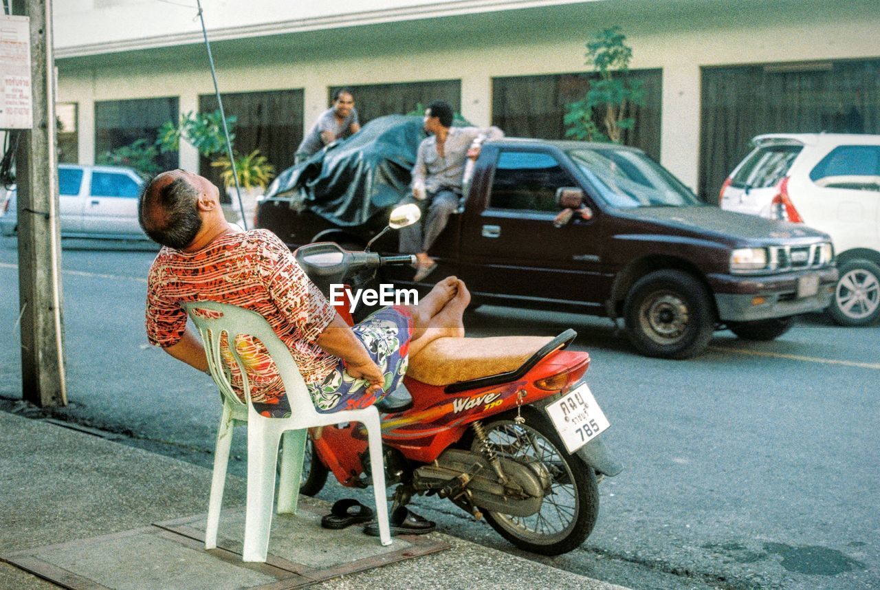 REAR VIEW OF MAN RIDING BICYCLE ON STREET