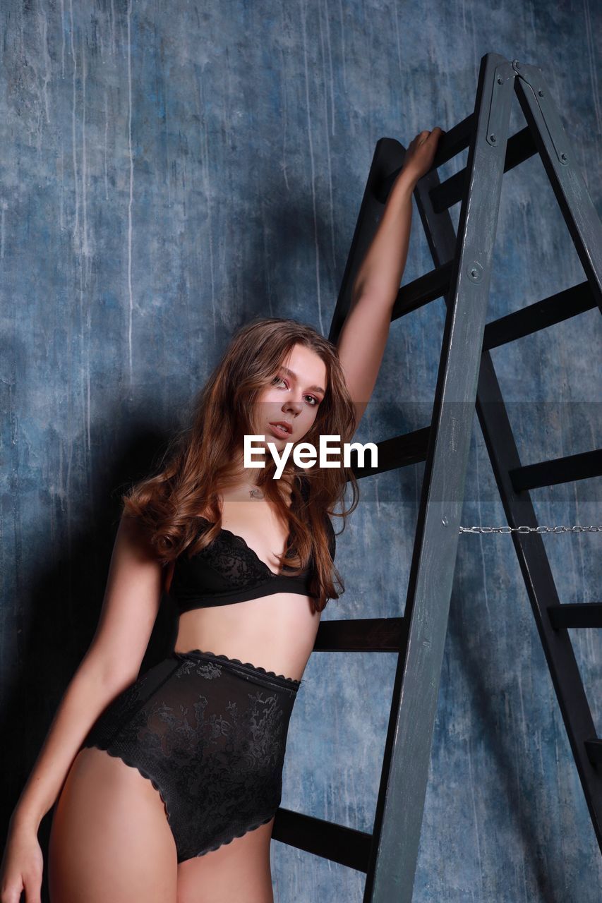 Portrait of beautiful teenage girl standing on ladder