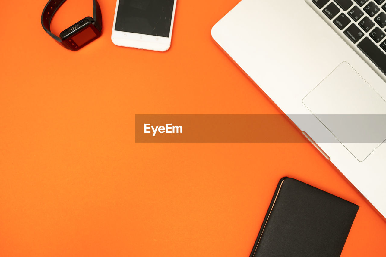 HIGH ANGLE VIEW OF LAPTOP ON TABLE AND ORANGE