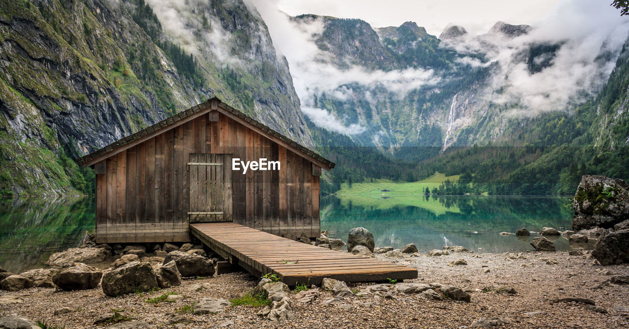 Log cabin by obersee lake amidst mountain during foggy weather