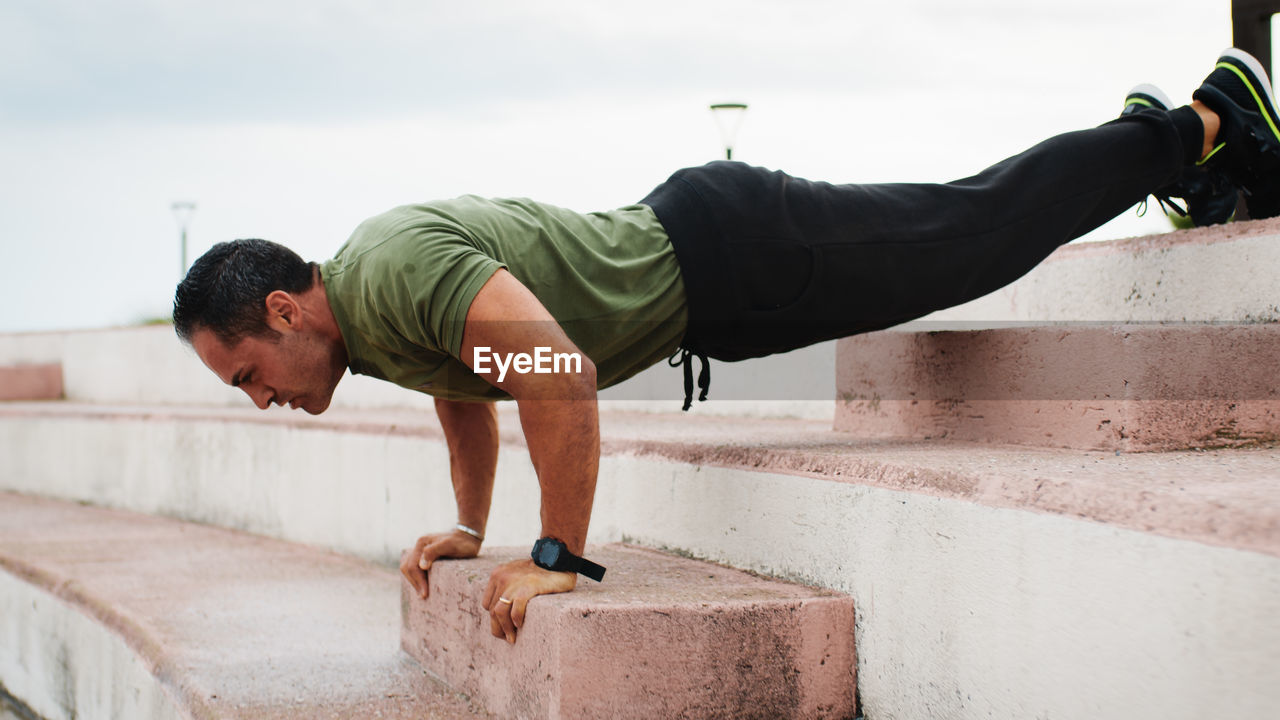 Man doing push up on the step outdoor during rainy day