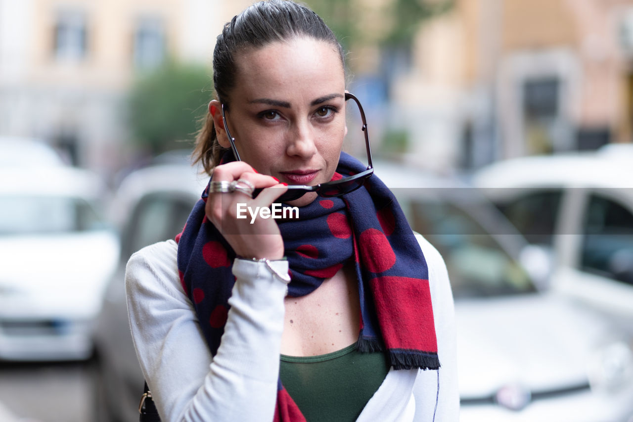 Portrait of woman wearing sunglasses while standing in city