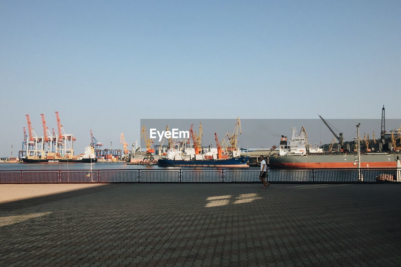 Man walking by boats moored at commercial dock