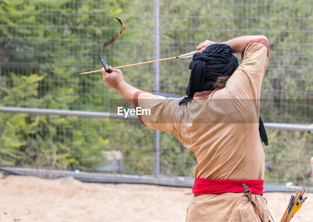 Rear view of man targeting with archery bow