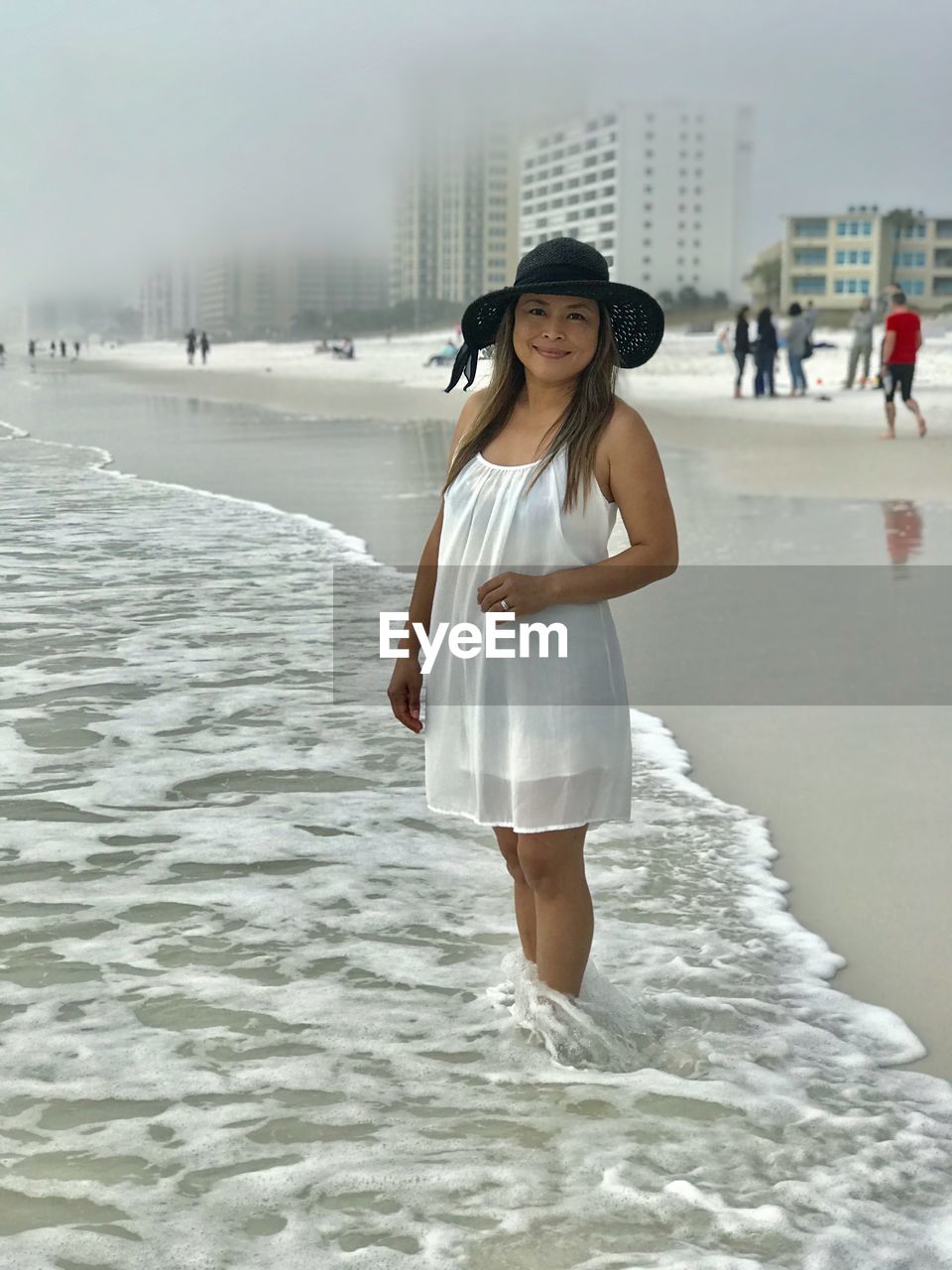 Portrait of smiling woman in hat standing at beach