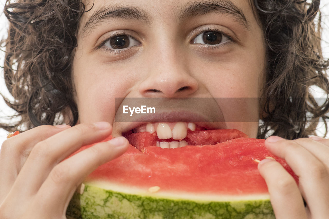 Close-up portrait of young man eating watermelon