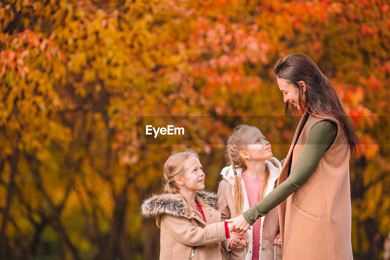 REAR VIEW OF A GIRL HOLDING AUTUMN LEAF