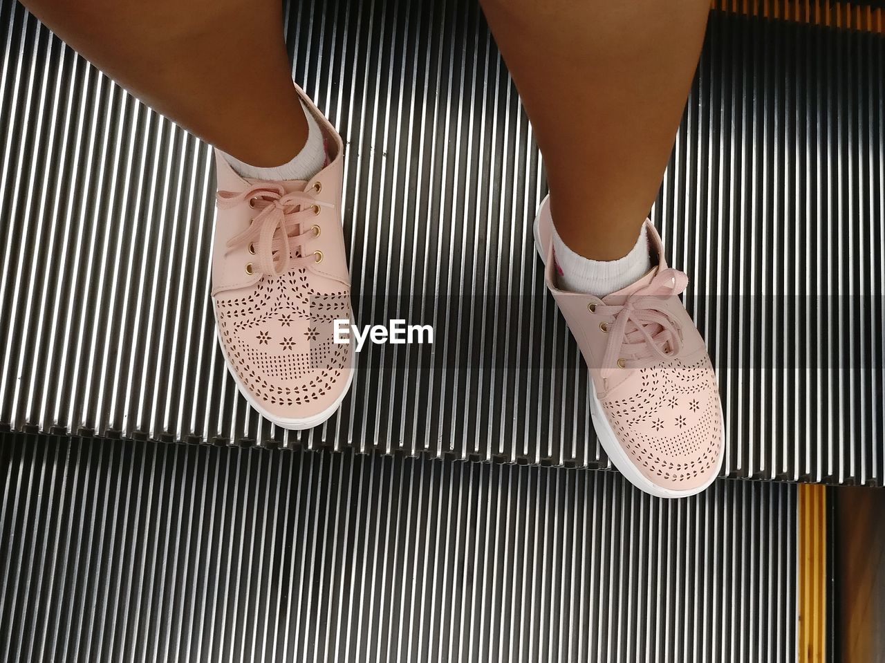 Low section of woman standing on escalator