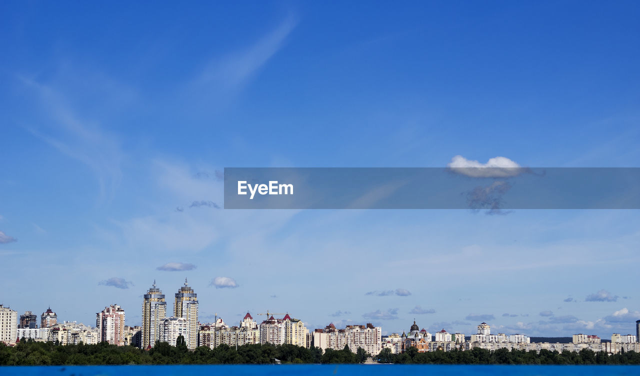 Dnieper river by buildings against cloudy sky