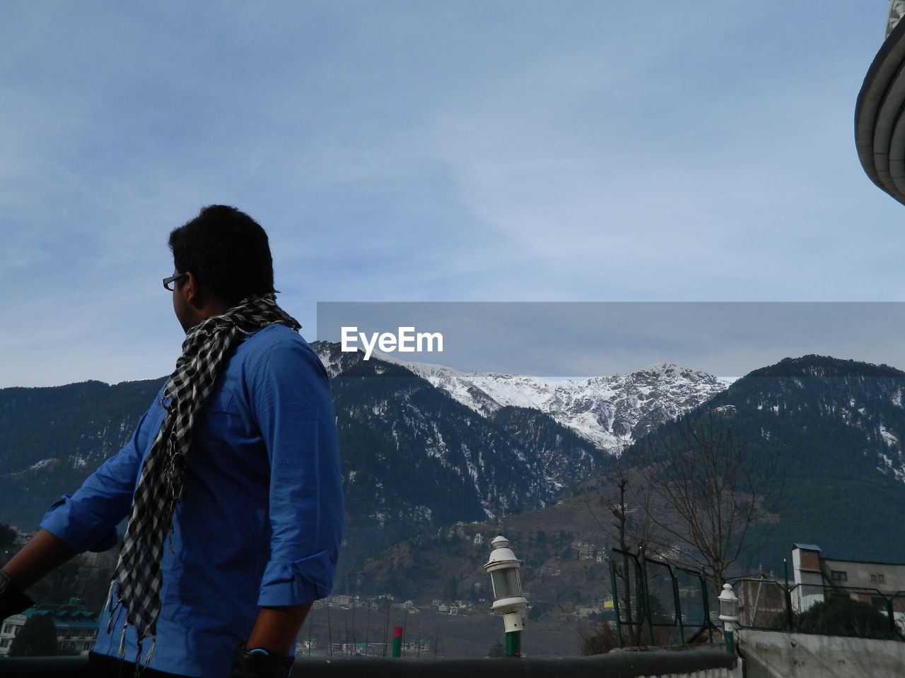 Man looking at mountains against sky during winter