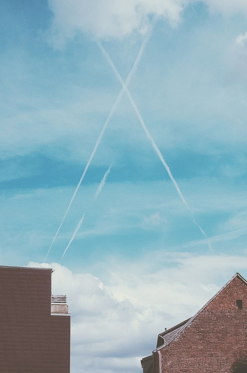 Low angle view of vapor trails in cloudy sky