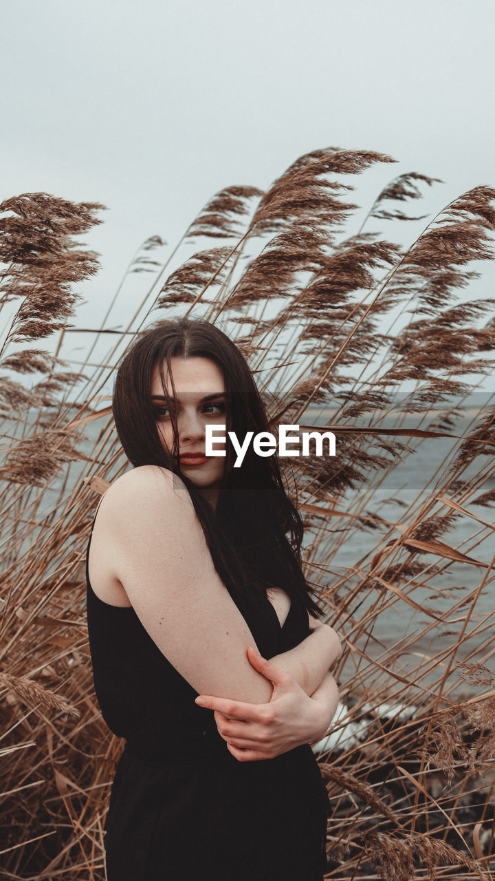 Portrait of beautiful young woman standing next to water