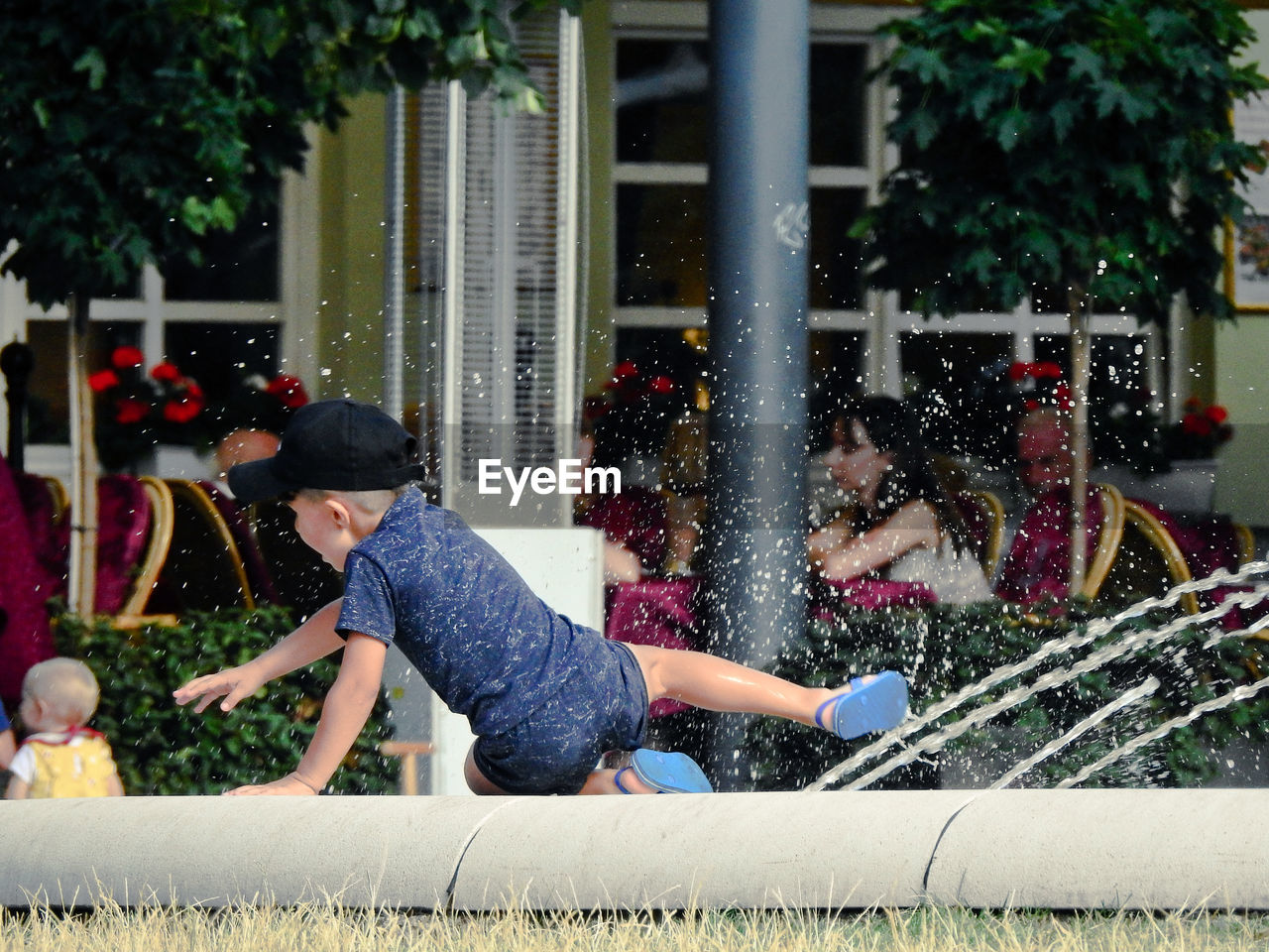 Full length of boy sitting by fountain outdoors