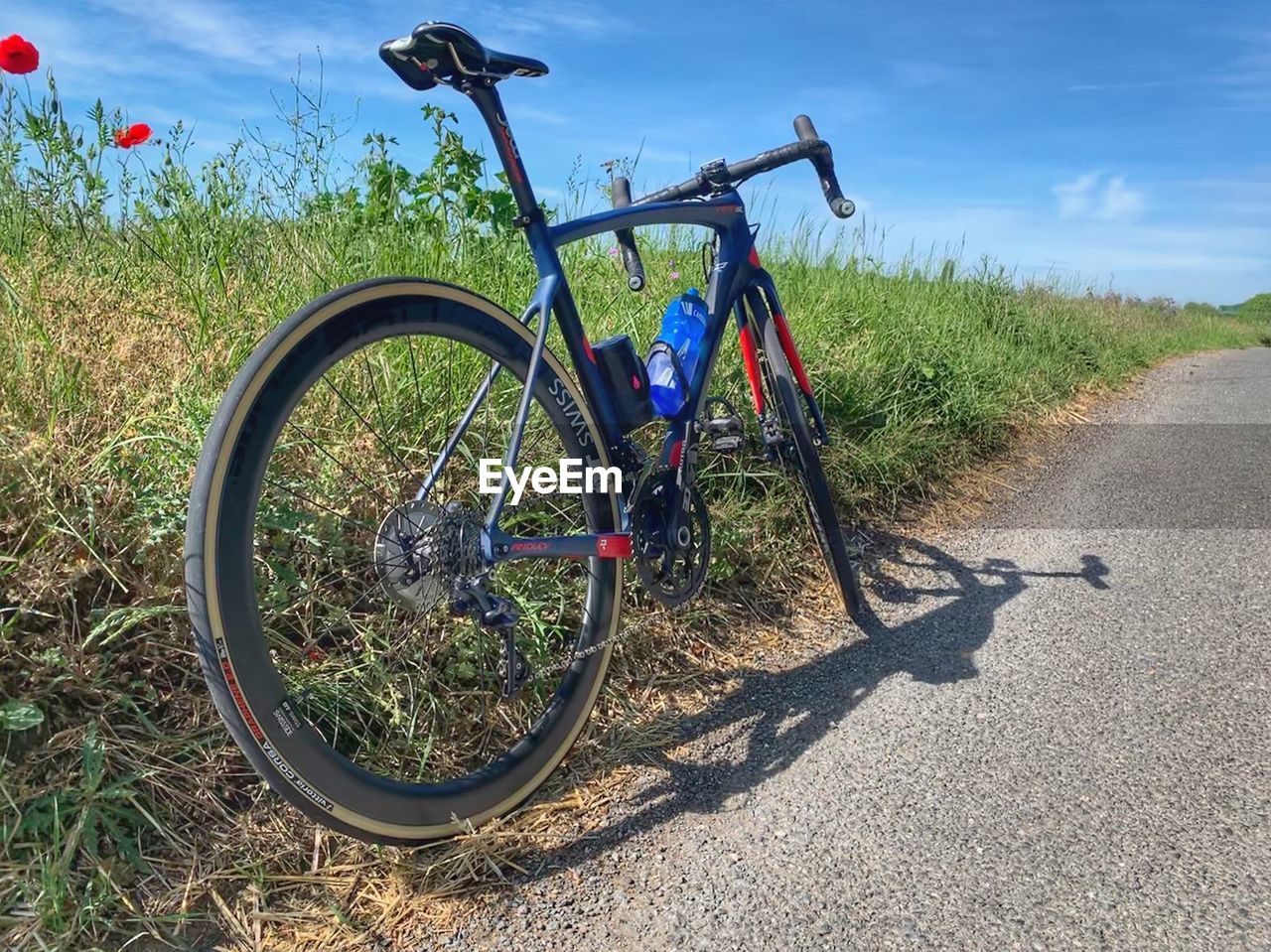 BICYCLE PARKED ON ROAD AMIDST LAND