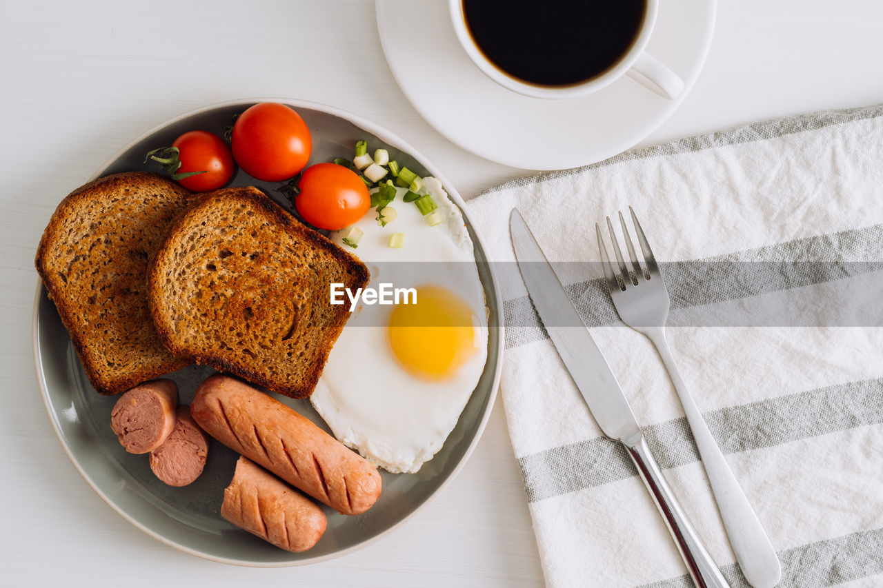 Breakfast plate with cup of black coffee, grilled sausage and whole wheat toast
