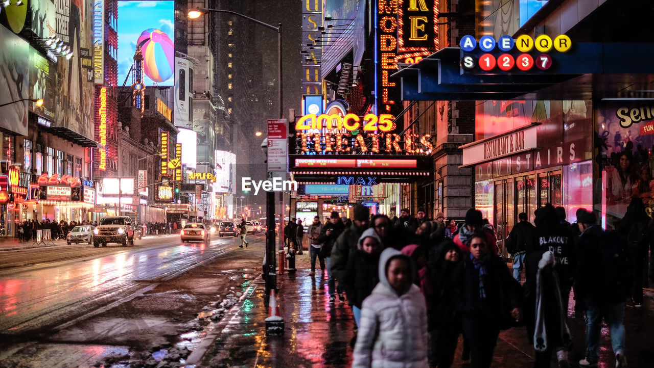 People walking on sidewalk in city during rainy season