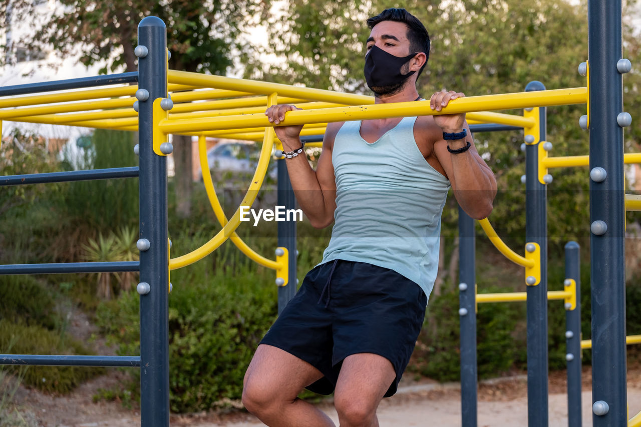 Young man wearing mask exercising outdoors