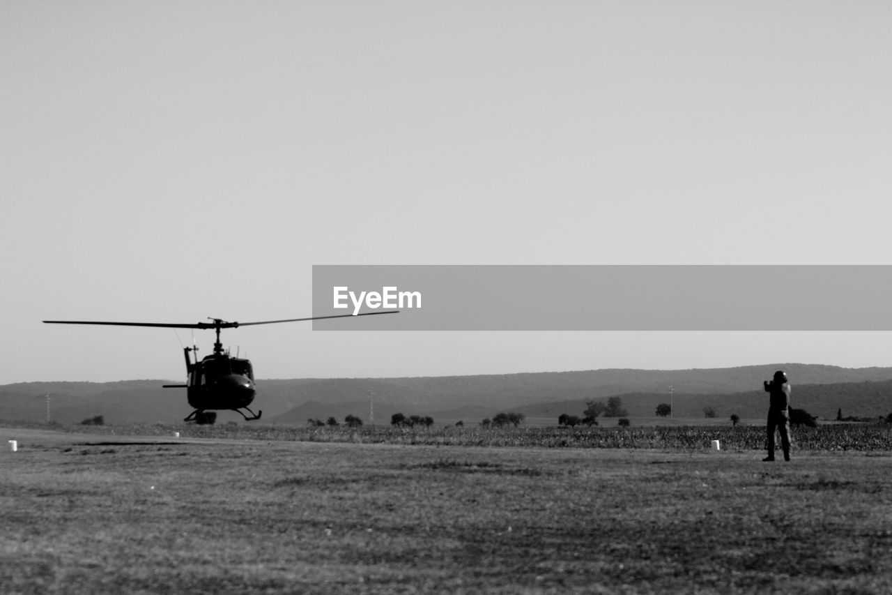 AIRPLANE FLYING OVER LAND AGAINST SKY