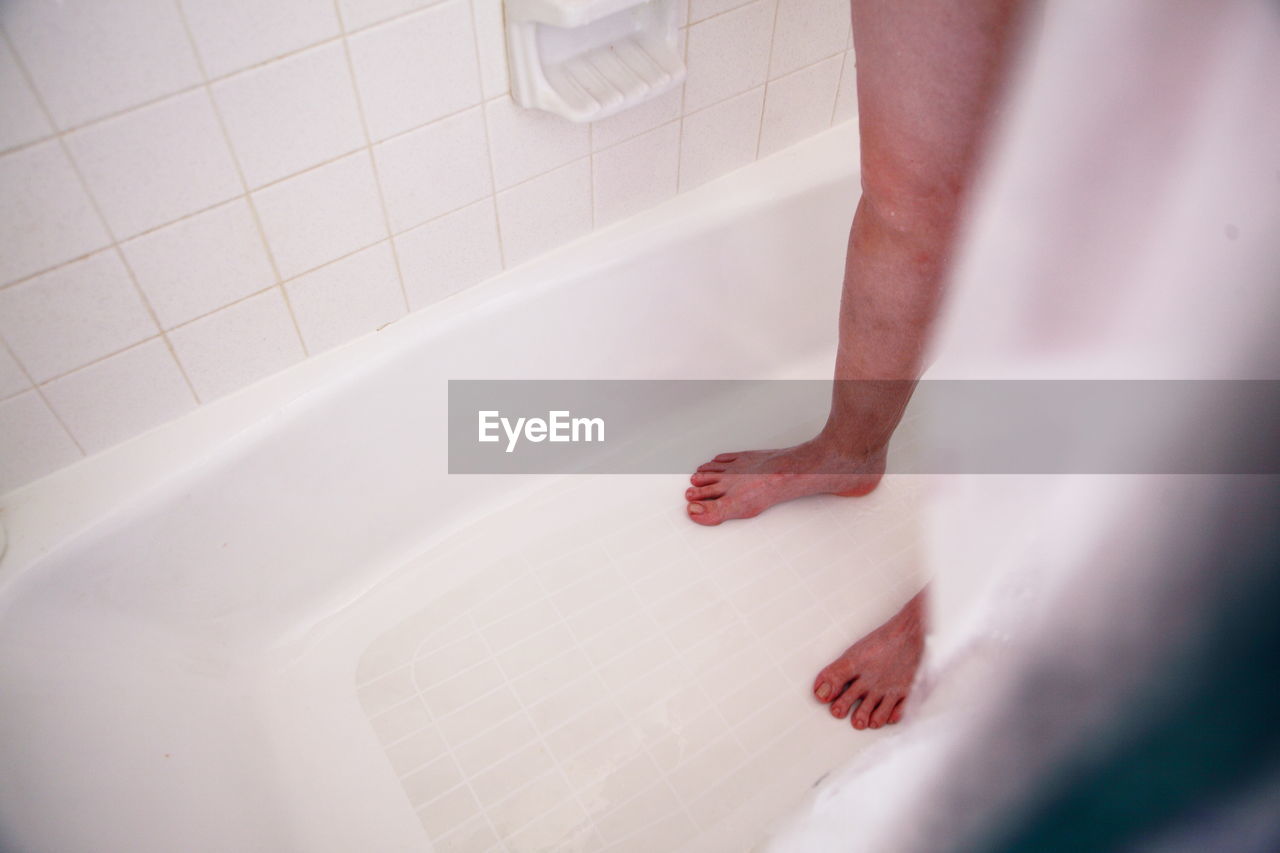 Low section of person standing in bathtub