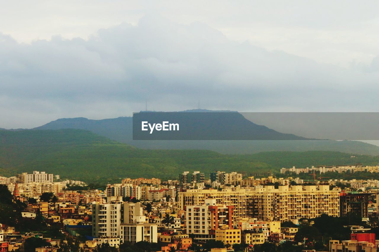 HIGH ANGLE VIEW OF TOWNSCAPE BY MOUNTAINS AGAINST SKY