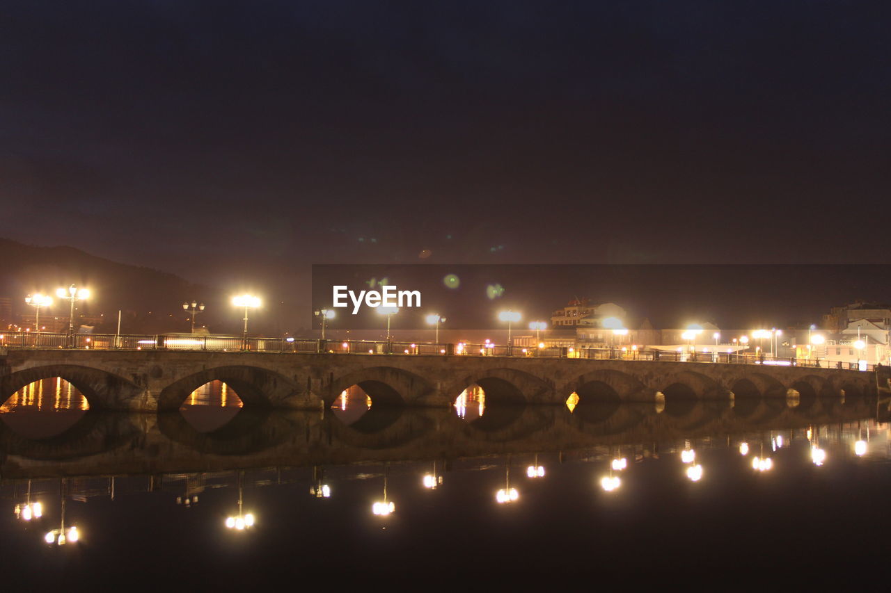 Illuminated burgo bridge over lerez river against sky at night