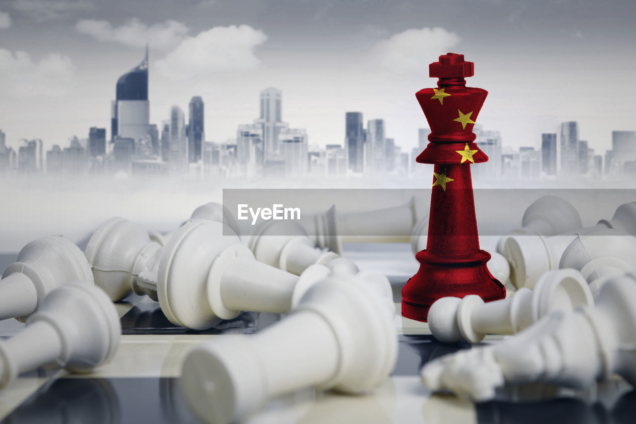 Digital composite image of chess pieces with flag against buildings in city