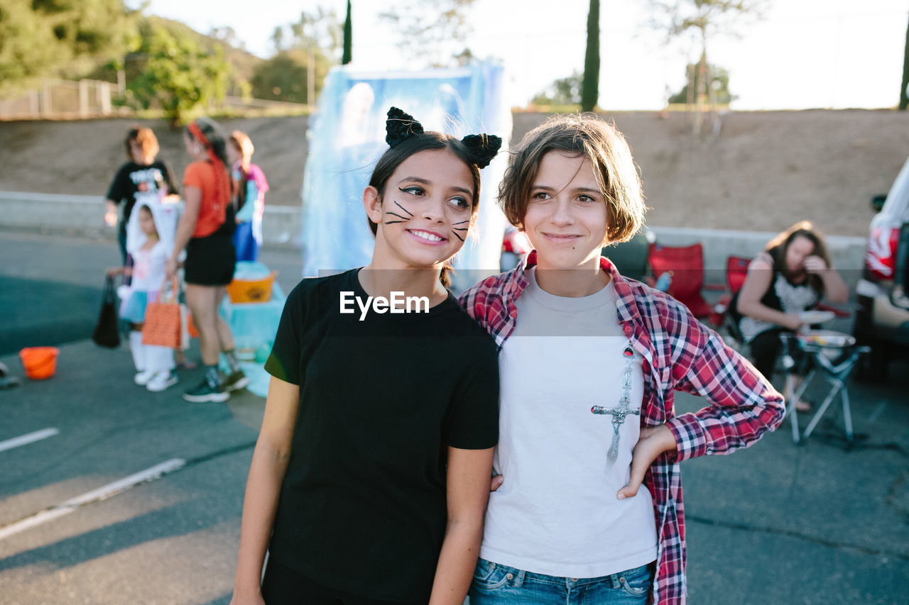 Young teen girls stand together at a halloween trunk or treat event